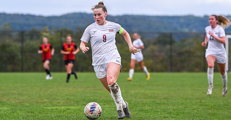 An IUP soccer player taking the ball down the field