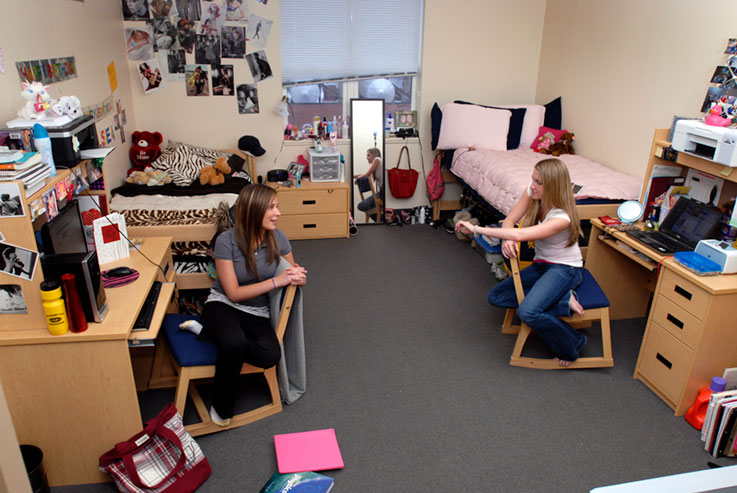 Two students talking at their desks in a room within one of the Suites on Grant buildings 