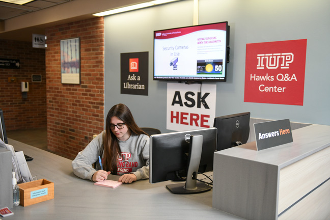 A student sits behind the Hawks Q&A desk, ready to provide answers