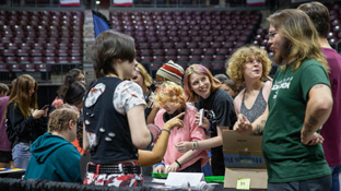 A mixed group of students talking to other students at a table in the KC during an event to promote student organizations