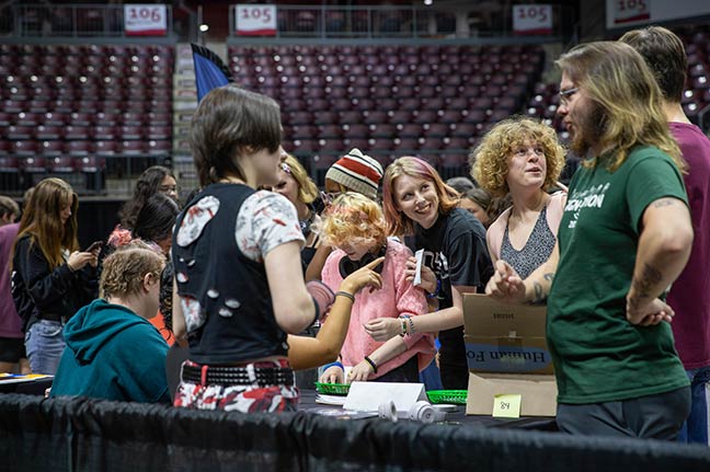 A mixed group of students talking to other students at a table in the KC during an event to promote student organizations