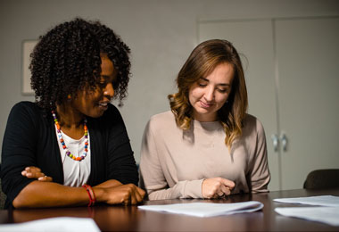 two students sitting at a table reviewing a paper