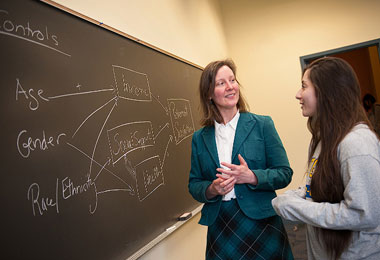 a professor and student standing in front of a chalkboard