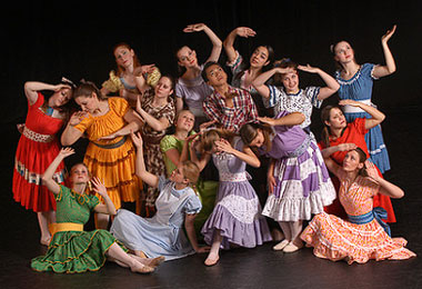 a group of students in stage costume posing for the camera in front of a black backdrop