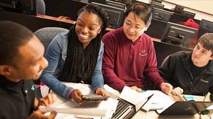 Group of 4 students sitting around a table smiling with eachother