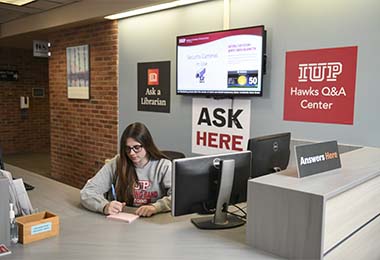 A student sits behind the Hawks Q&A desk, ready to provide answers