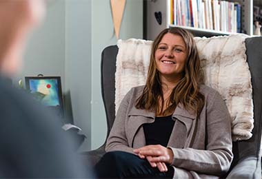 a woman sitting and smiling in a chair