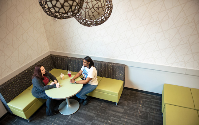 shot from above of a navigator and student talking in the corner of an open dining hall