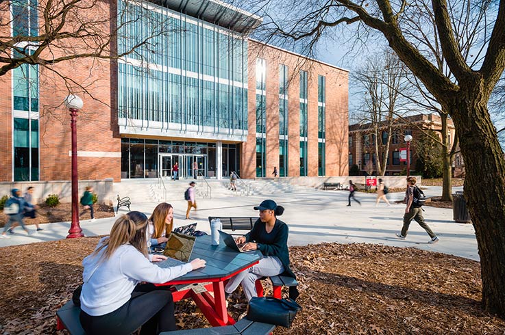 Exterior of Kopchick Hall with students walking past in foreground and background