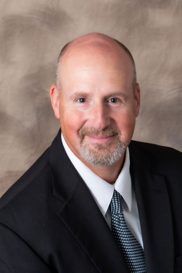 Professional head-and-shoulders portrait of Craig Killian on a beige, textured background