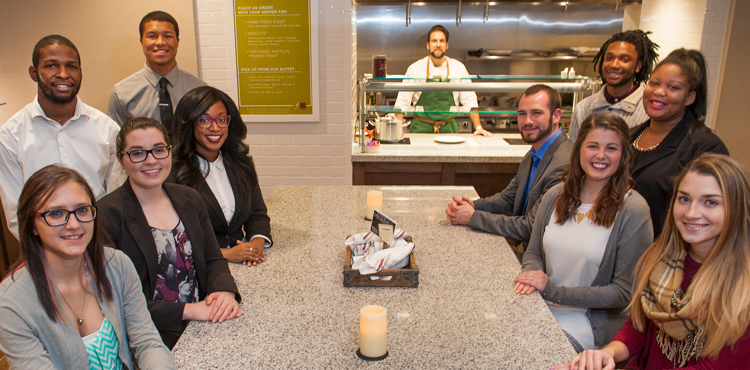 Students gather around a table for a meeting in a dining area