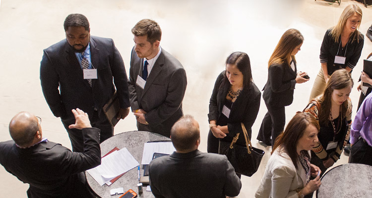 Students stand at a table and talk with employers at IUP Business Day