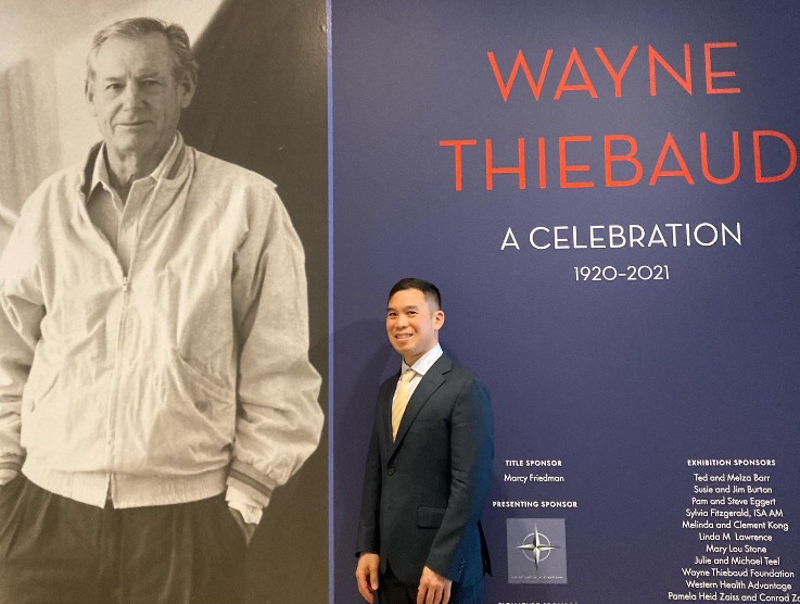 Henry Wong Doe in front of a poster for the Wayne Thiebaud concert