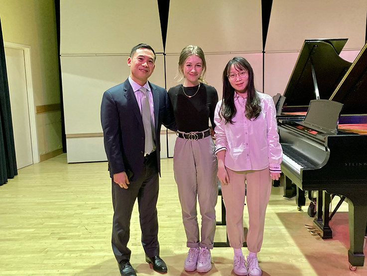 Henry Wong Doe with two students in front of a piano at Duquesne