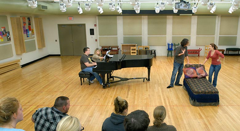 Two students act, while a student at the piano waits to accompany them.