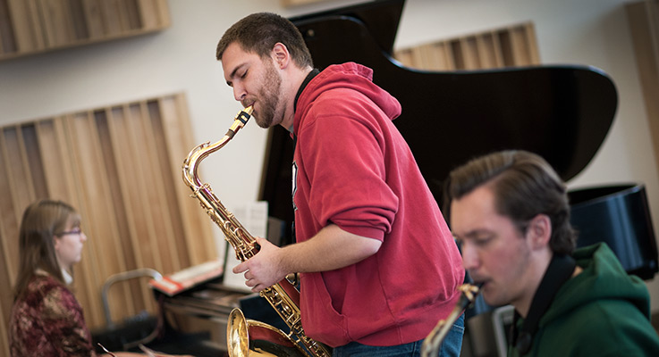 A student plays the saxophone in a rehearsal.