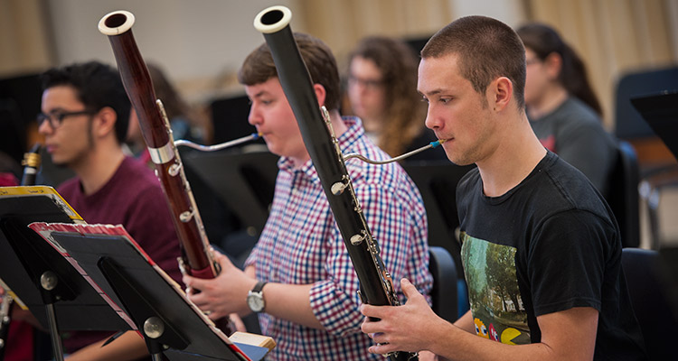 Students playing woodwind instruments in a rehearsal