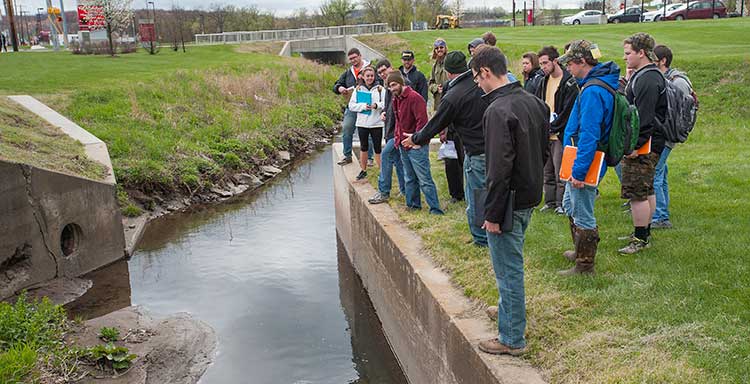 Students stand next to water with professor Richard Hoch 