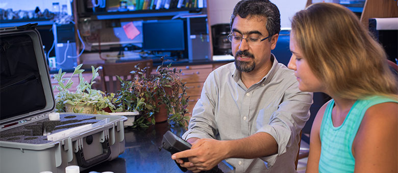 Professor (and Environmental Engineer) Sajad Hamidi explains a piece of lab equipment to an Environmental Engineering student