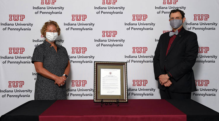 Bonnie Anderson and President Driscoll stand with the Resolution plaque