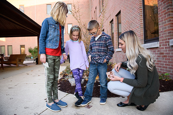 A student teacher talks with three children at the Sobotka Science Discovery and Outdoor Learning Center. 