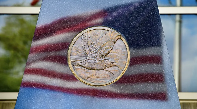 close up of a memorial with the american flag reflecting on the surface