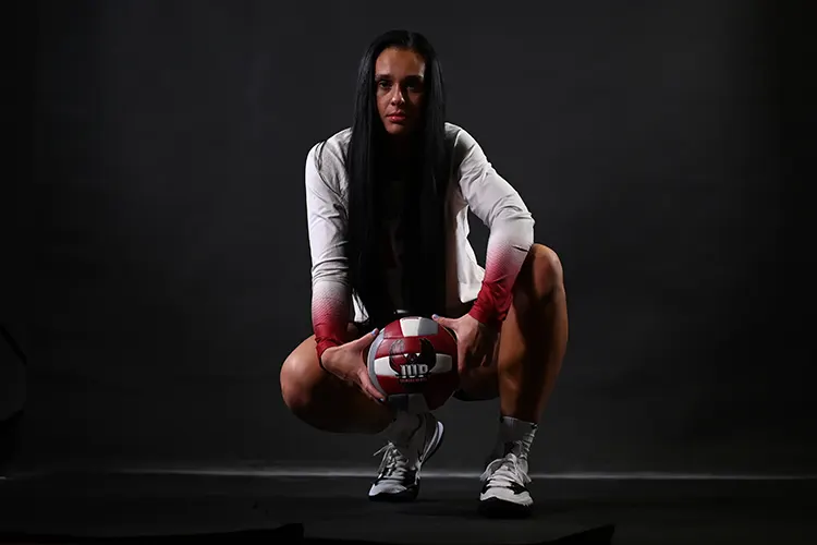 Caroline Walsh crouched and holding a volleyball