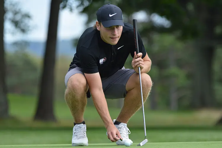 Shaun Fedor crouched on a gold course examining his shot