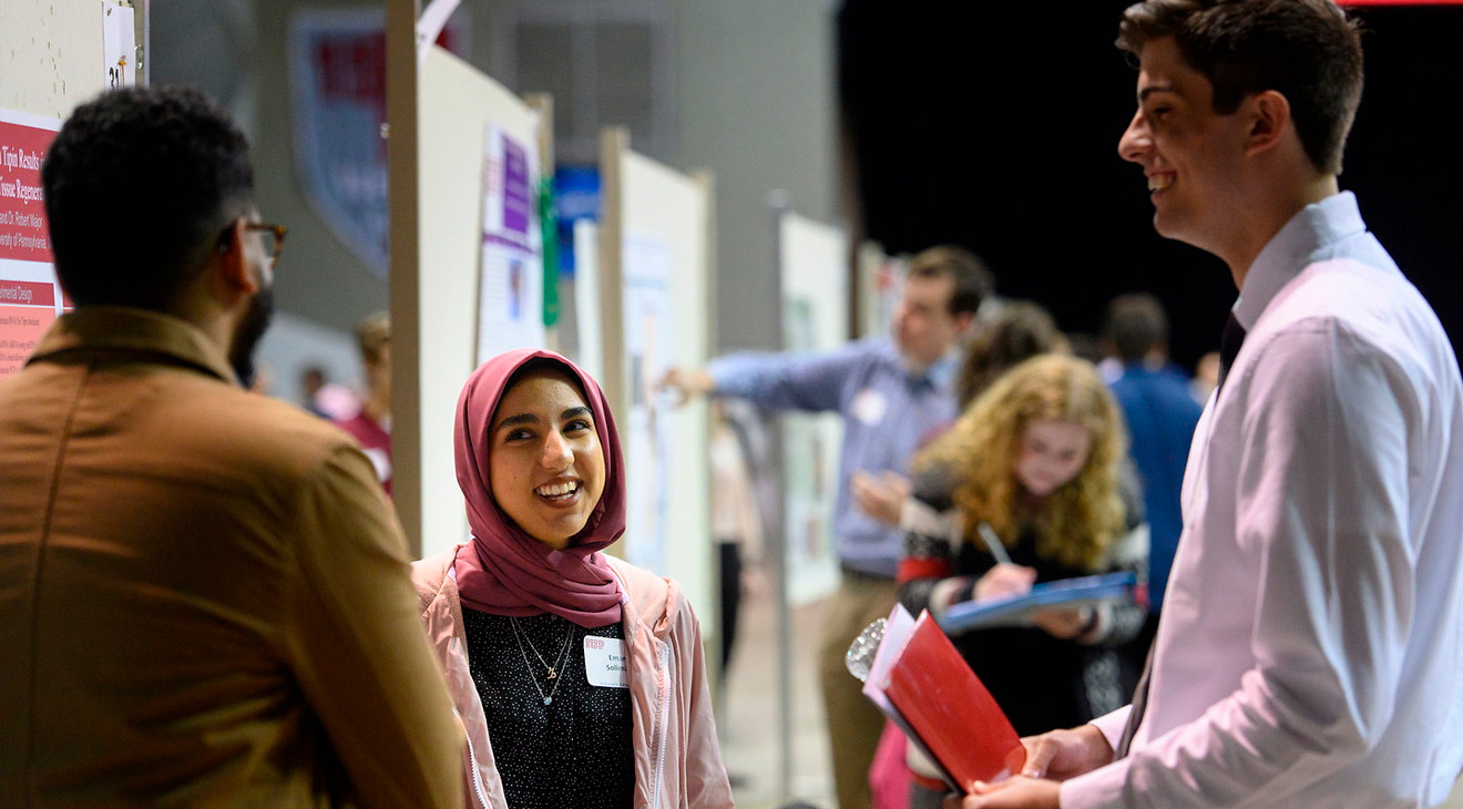 Three students at a conference standing in a circle talking