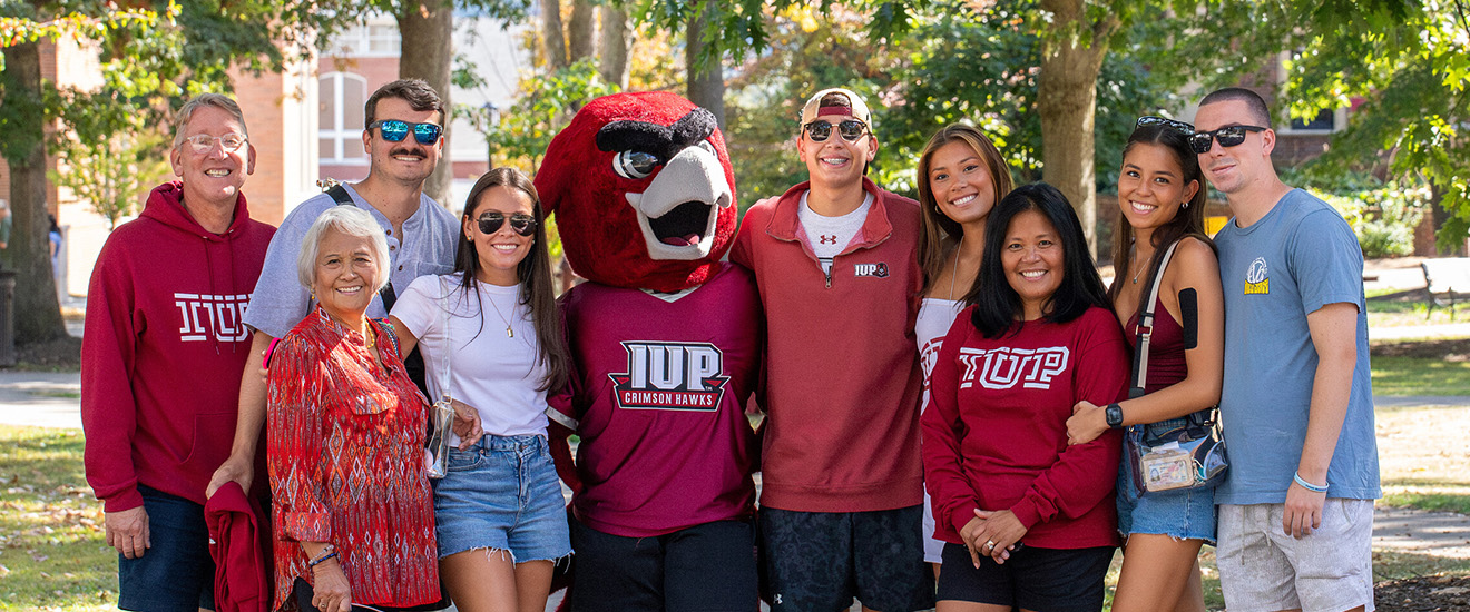 A large family poses with Norm in the Oak Grove during Family Weekend.