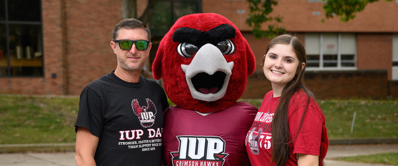 A father and daughter pose with Norm in the Oak Grove on Family Weekend. 
