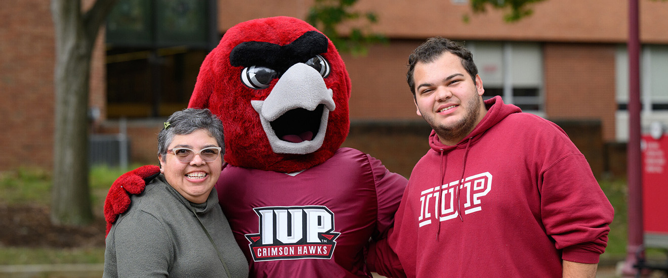A mother and son pose with Norm in the Oak Grove on Family Weekend. 