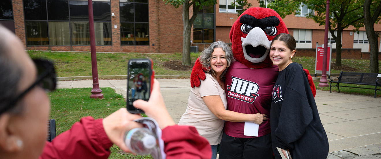 Someone take a photo on a phone of a mother and daughter in the Oak Grove on Family Weekend. 