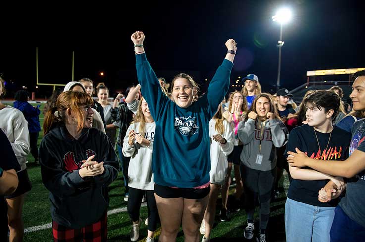 Students cheering on the football field at night