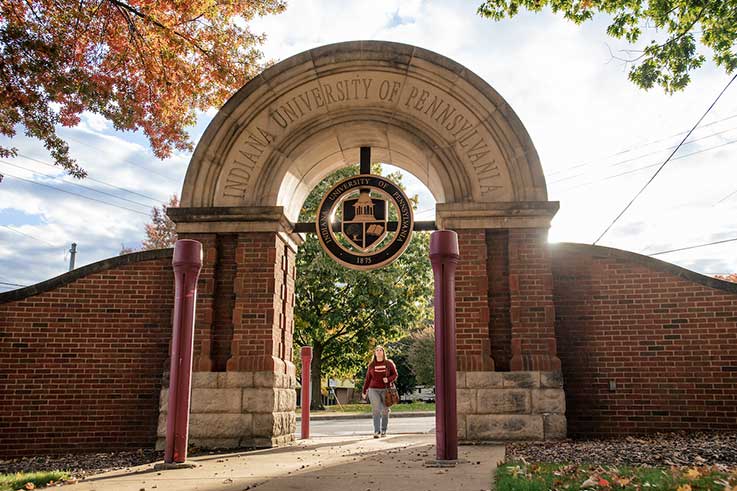 White IUP logo sitting on top of a red wood grain background