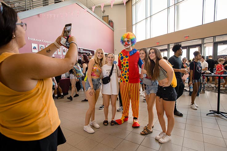 Four IUP students having their photo taken by another while posing with a clown, in the KCAC lobby.