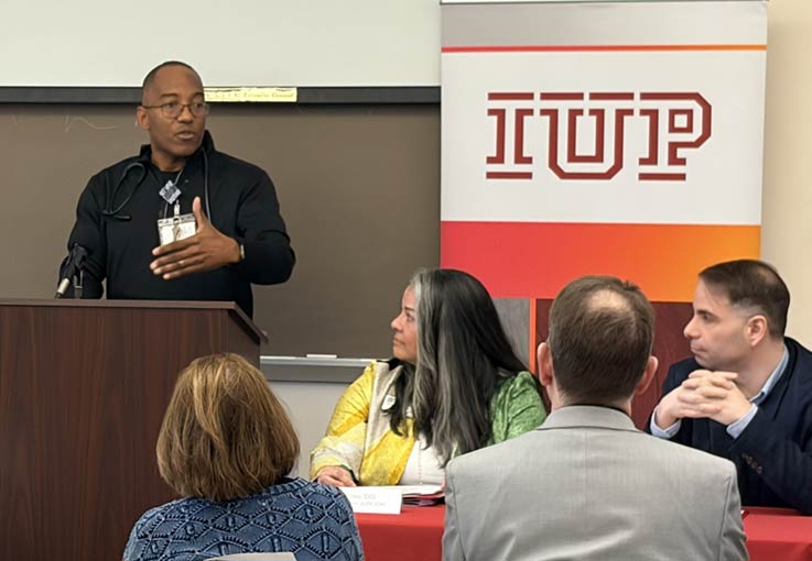 Sharon Regional Health System Medical Director of Emergency Services Christopher Conti at podium, with IUP proposed college of osteopathic medicine Founding Dean Miko Rose and IUP proposed college of osteopathic medicine Founding Associate Dean of Clinical Affairs and Graduate Medical Education Ryan Smith