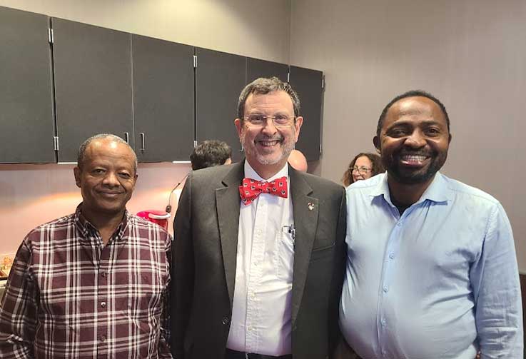 three men standing side by side smiling for the camera