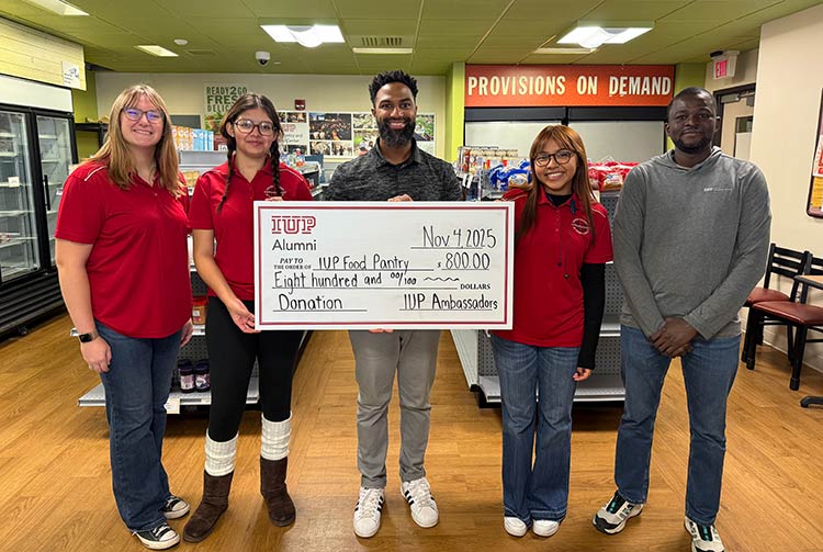Members of the IUP Ambassadors, IUP Food Pantry and Help Center, and Student Inclusion posing inside the Food Pantry with a large donation check for the Pantry
