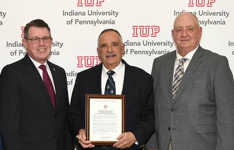 White IUP logo sitting on top of a red wood grain background