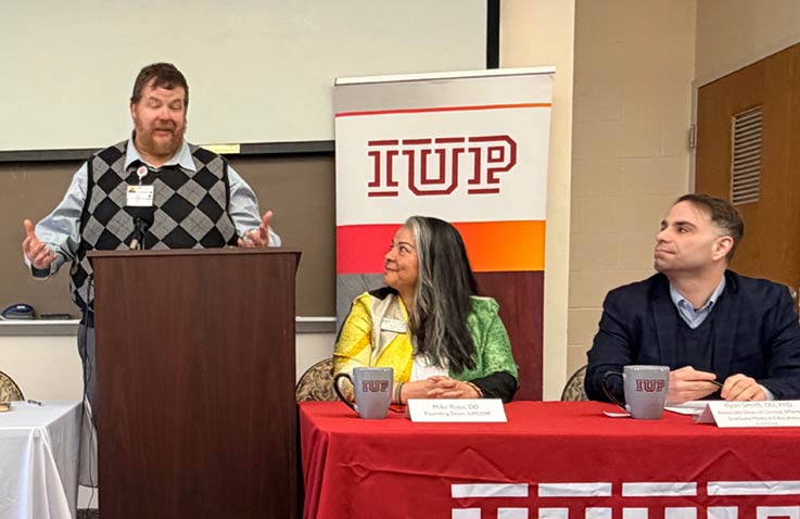 Sharon Regional Health System Chief Medical Officer Jeremy Mashburn at podium, with IUP proposed college of osteopathic medicine Founding Dean Miko Rose and IUP proposed college of osteopathic medicine Founding Associate Dean of Clinical Affairs and Graduate Medical Education Ryan Smith