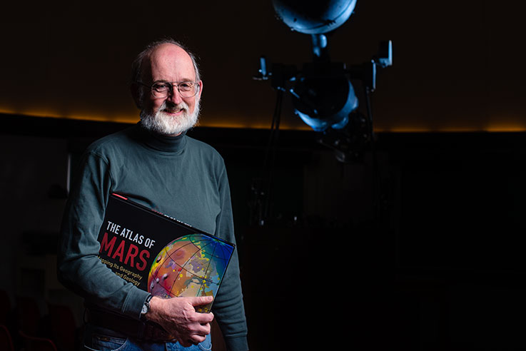 Ken Coles in the IUP Planetarium holding the Atlas of Mars 