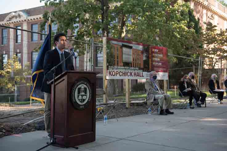 Marcos Zegarra, student speaker, at the podium with other attendees in the background