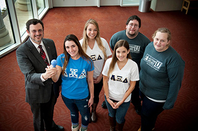 IUP President Michael Driscoll receives a blue light bulb from Alpha Xi Delta sorority members and Autism U members for Autism Awareness Month