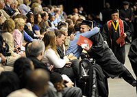 A new graduate gets a hug from an audience member during the May 2011 commencement ceremony