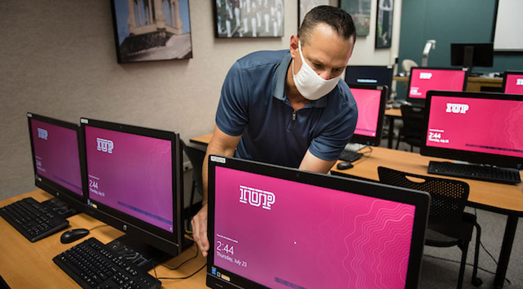 IUP staff working on computer with PPE