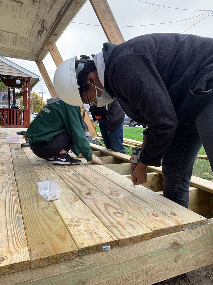 An IUP Habitat for Humanity volunteer secured a wooden plank to a deck.