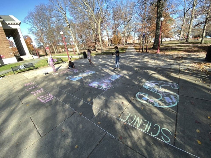 National Art Education Association members created chalk art outside Fisher Auditorium last fall to promote the “A” (art) in STEAM. From left: Sydney Huston, Davey Beyer, Tristan Croyle, and Jen Freno.