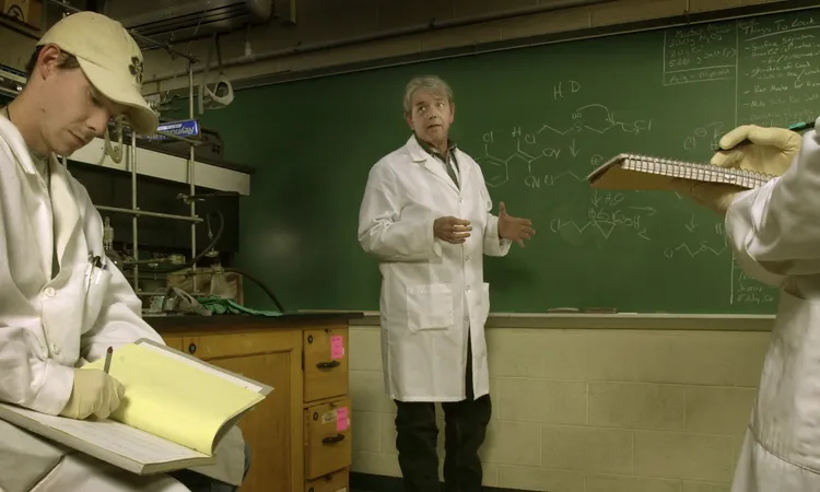 a man in a white lab coat talking in front of a chalkboard