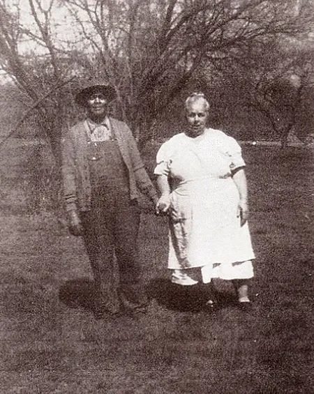 Old black-and-white photograph of a couple holding hands in a field